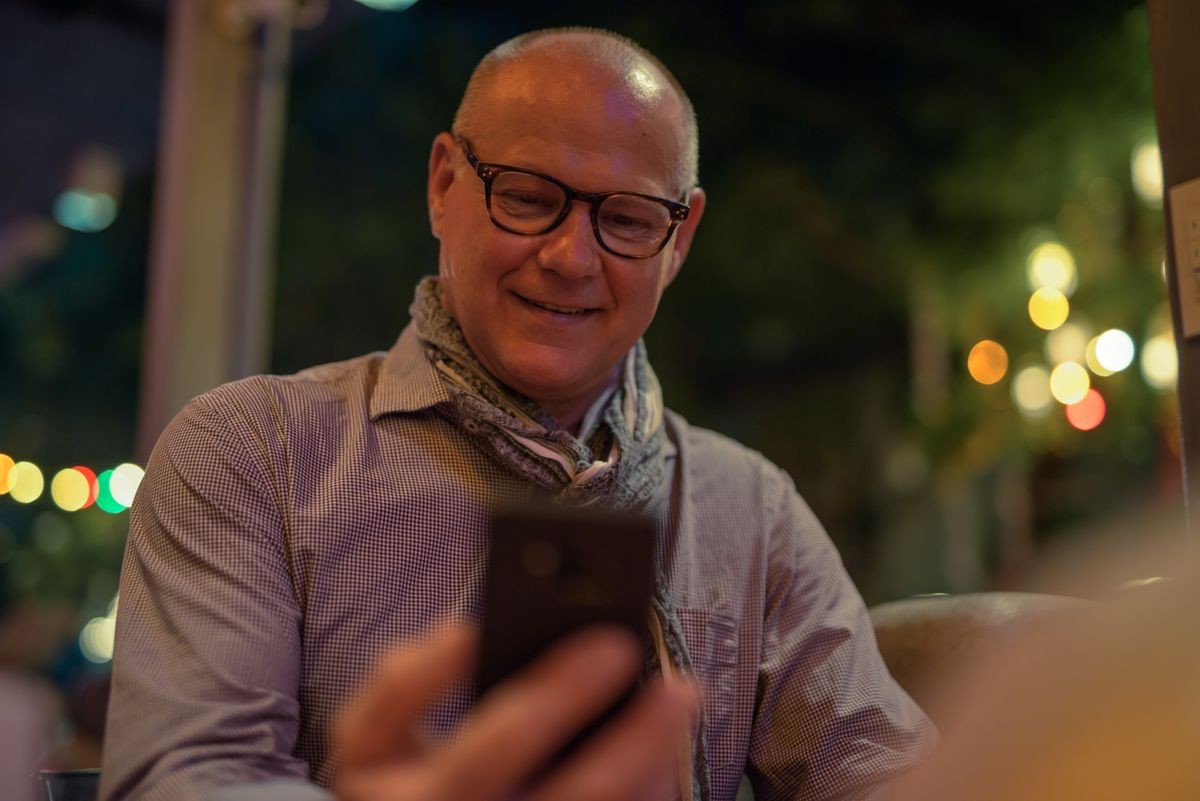 Portrait of senior handsome Scandinavian tourist man exploring the city streets at night